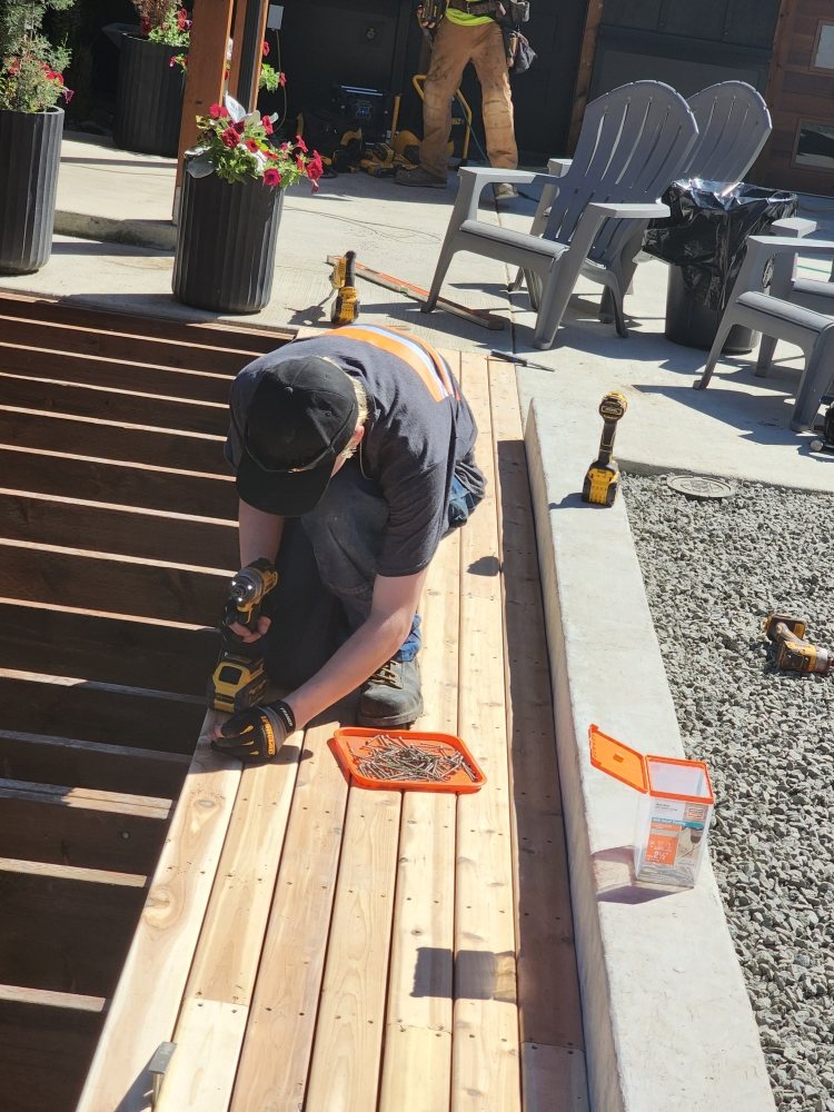 Carpenter fastening cedar deck boards with a drill
