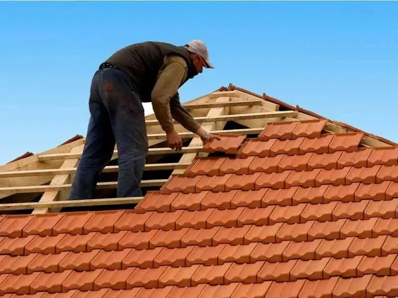 Roofer installing tile roofing on a home